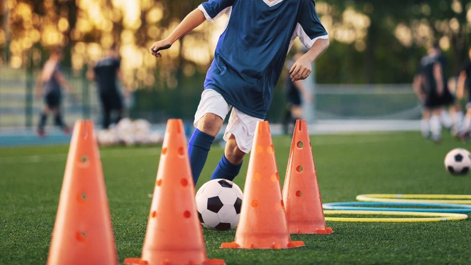 サッカースクールでコーンドリブルしている画像